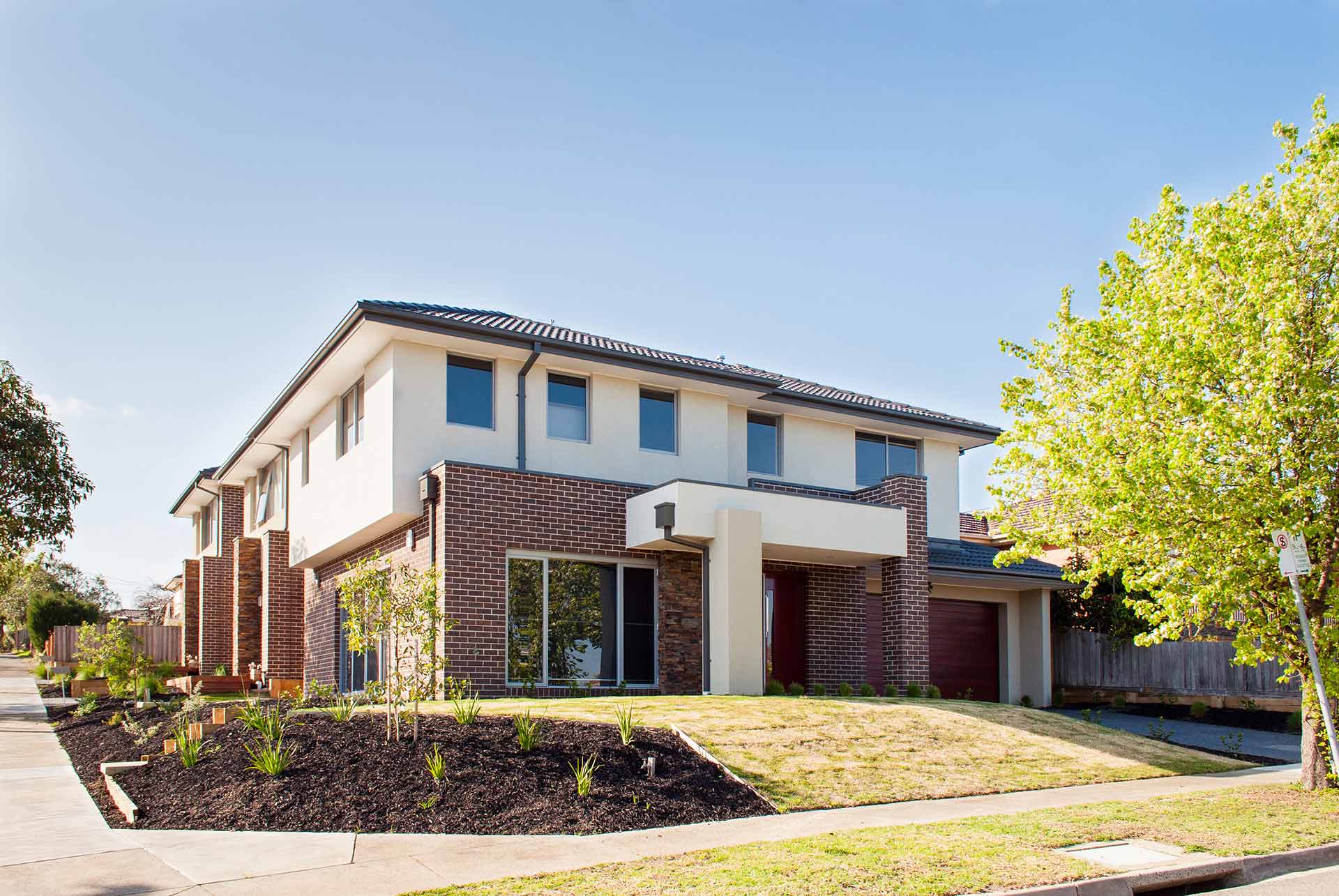 A contemporary home featuring a well-maintained driveway and attractive landscaping.