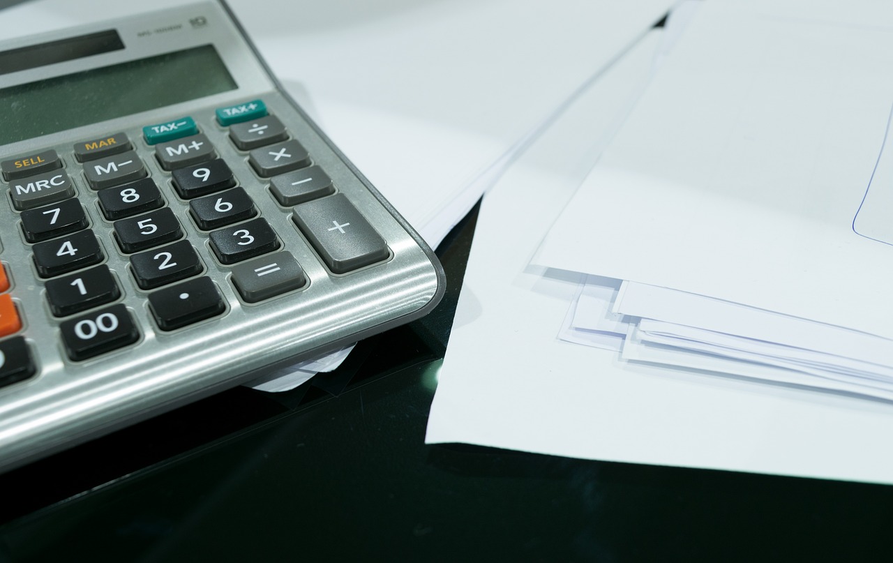 A desk featuring a calculator alongside various papers, representing organisation and analytical tasks.