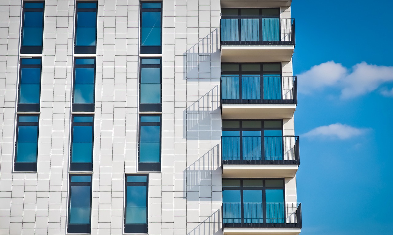 Modern apartment building featuring multiple balconies and large windows, showcasing contemporary architectural design.