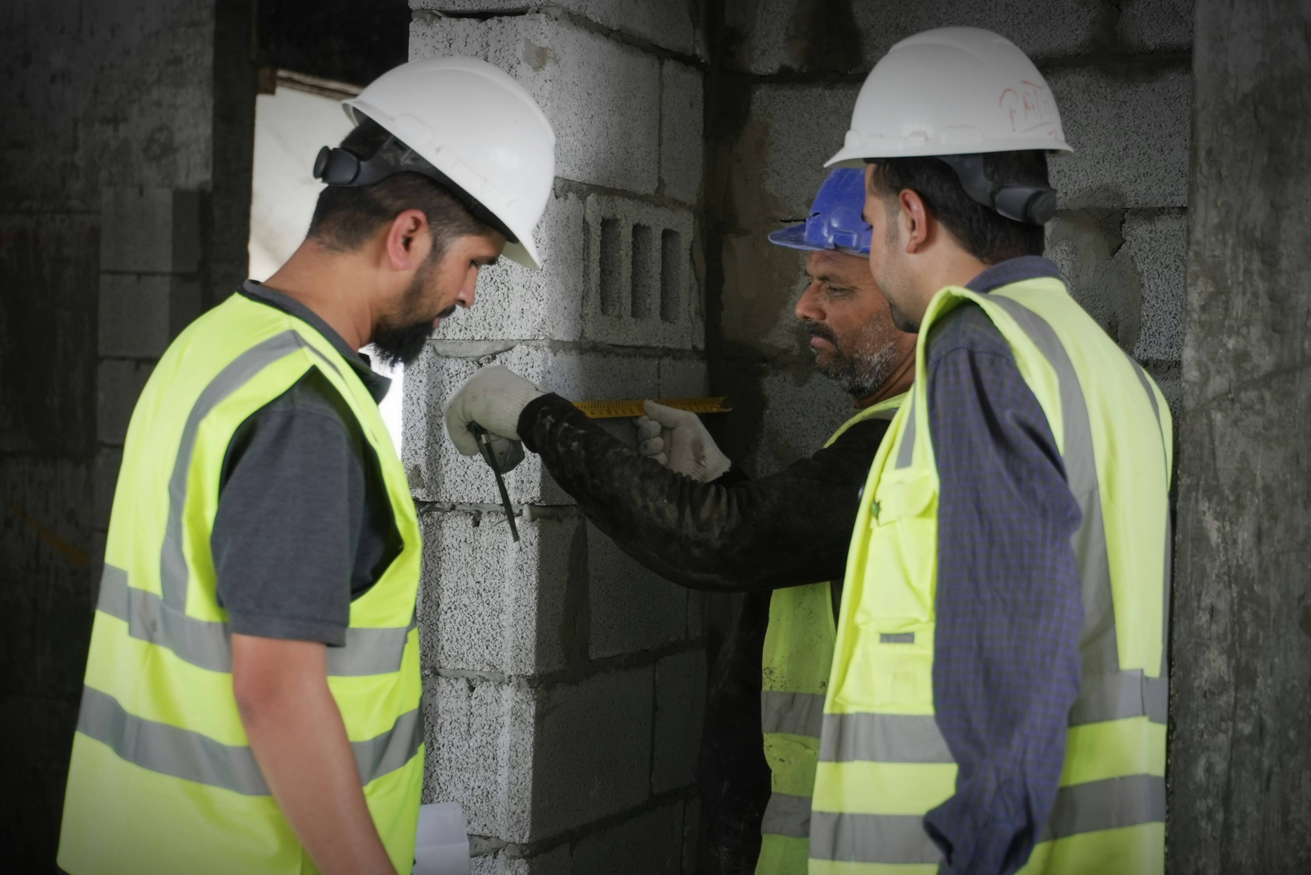 A couple of men standing next to each other on a building site.