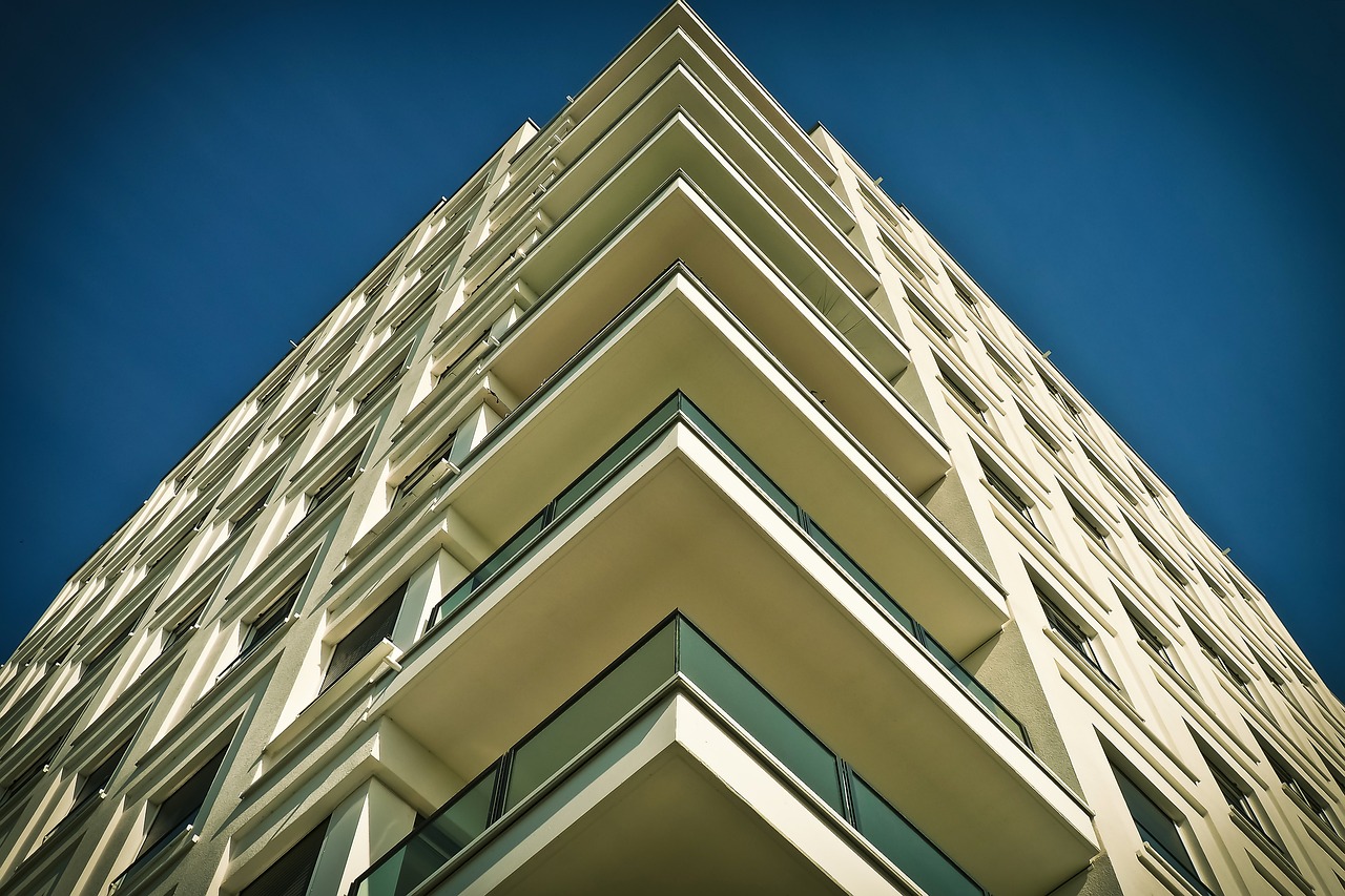 A tall building featuring a curved balcony against a clear blue sky, showcasing modern architectural design.