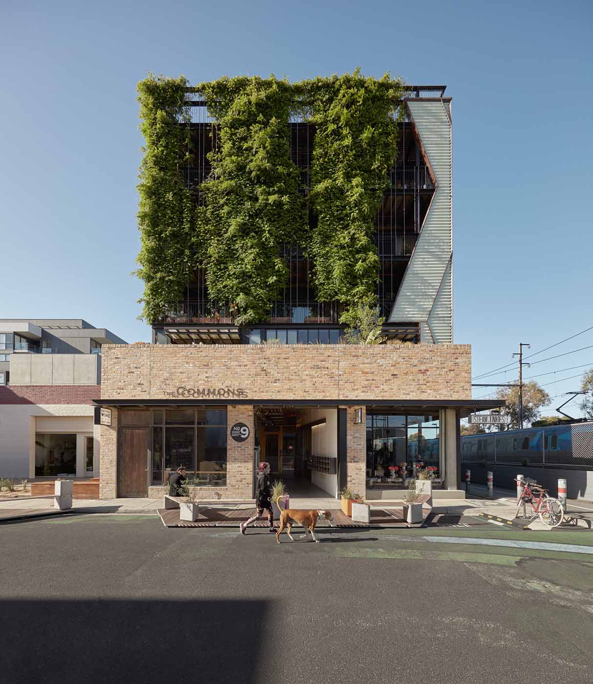A brick building adorned with lush green plants climbing its sides, showcasing a blend of nature and architecture.